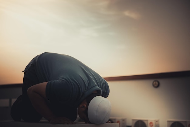 Un giovane uomo musulmano asiatico che prega sul concetto di festival del tramonto Ramadan