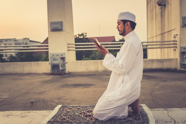 Un giovane uomo musulmano asiatico che prega sul concetto di festival del tramonto Ramadan