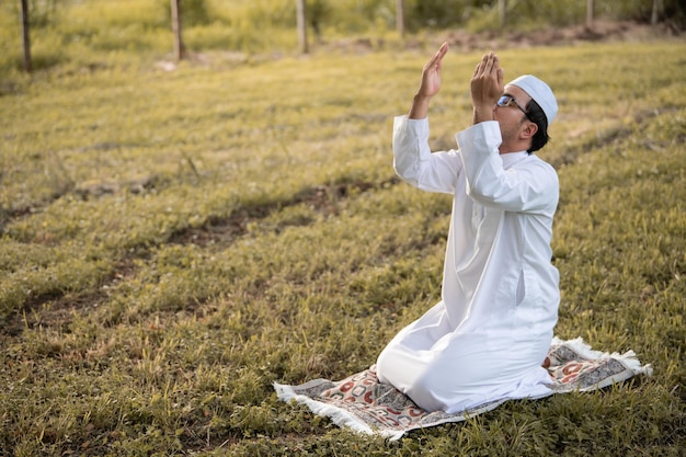 Un giovane uomo musulmano asiatico che prega sul concetto di festival del tramonto Ramadan