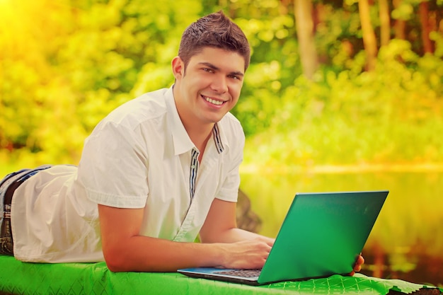 Un giovane uomo sorridente con il colore di instagram del laptop