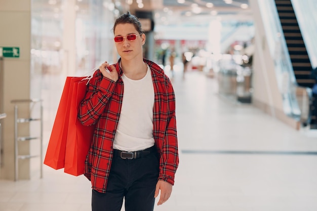 Un giovane va al negozio del centro commerciale con le borse della spesa