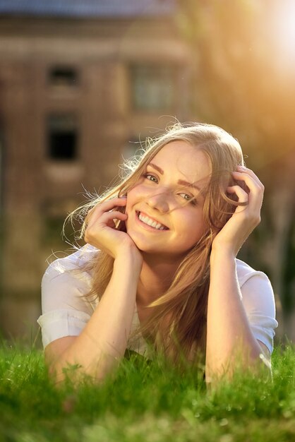 Un giovane womanl felice si trova in un prato verde sotto il sole estivo.