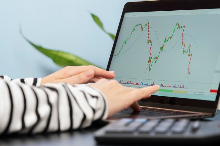 Un grafico in caduta sul monitor di un laptop e le mani pronte a fare un accordo di acquisto di azioni