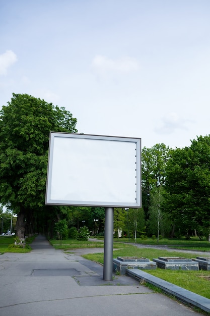 Un grande cartellone di metallo sulla strada con un posto per la tua pubblicità, un cartellone su uno sfondo di alberi