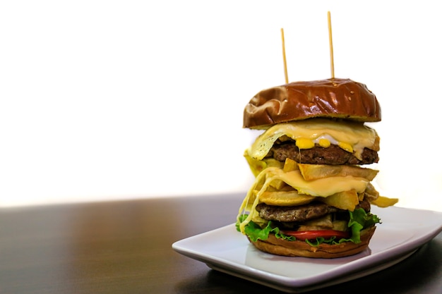 Un grande doppio hamburger su piatto di porcellana e sfondo bianco