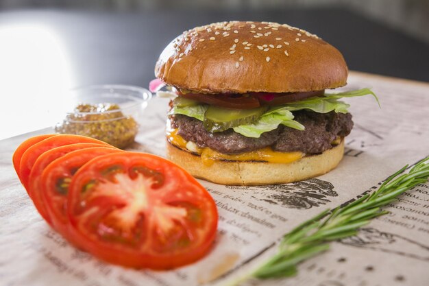 Un grande e gustoso hamburger con pomodoro a fette su un tavolo, in un bar