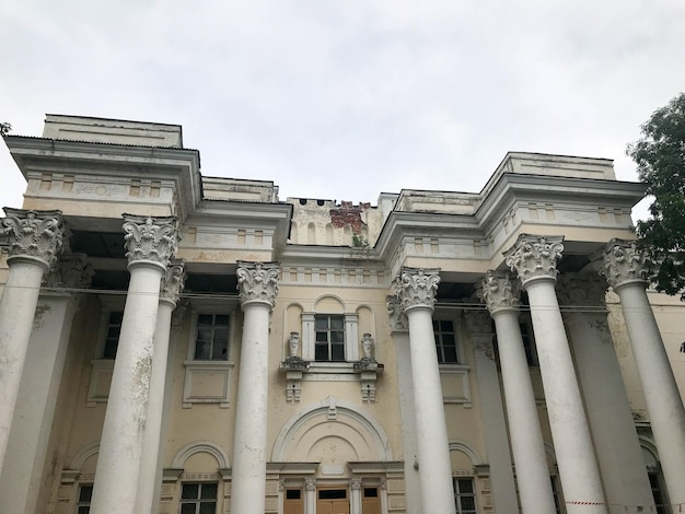 Un grande edificio bianco, antico e signorile, con colonne rotonde in pietra contro un cielo grigio