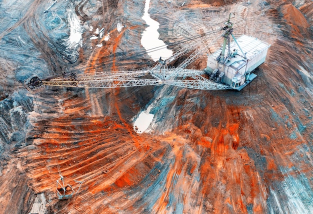 Un grande escavatore a piedi lavora in una cava per l'estrazione di metalli rari. Vista drone. Paesaggio industriale.