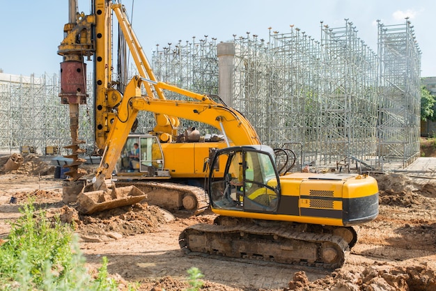 Un grande escavatore giallo con benna anteriore raccoglie terra in un cantiere durante la costruzione