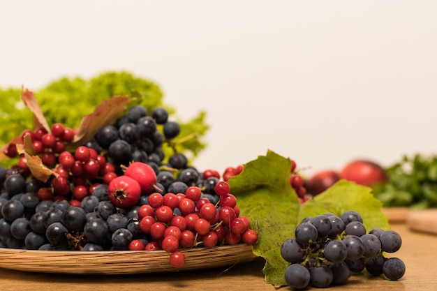 Un grande piatto con frutti autunnali e bacche si trova sul tavolo della cucina