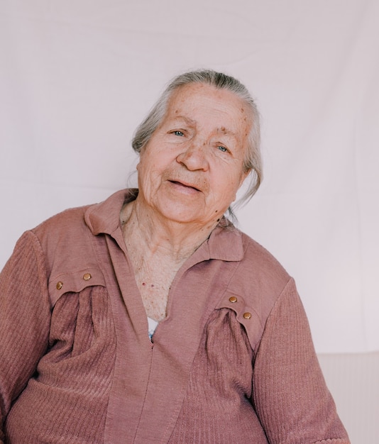 Un grande ritratto di una nonna con rughe profonde e macchie di vecchiaia sul viso.