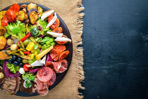 Un grande set di cucina italiana Carne di salsiccia di formaggio e verdure sottaceto su tavola di legno Vista dall'alto Spazio libero