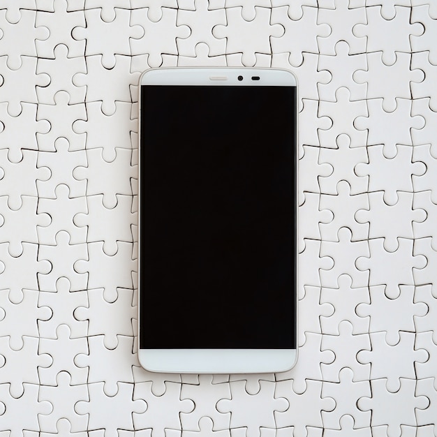 Un grande smartphone moderno con un touch screen si trova su un puzzle bianco in uno stato assemblato