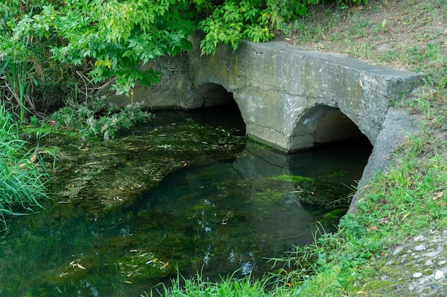 Un grande tubo di cemento per deviare il fiume sotto l'autostrada Acqua sporca che perde da grandi tubi di cemento Liquami sporchi dal tubo inquinamento ambientale Problema ambientale