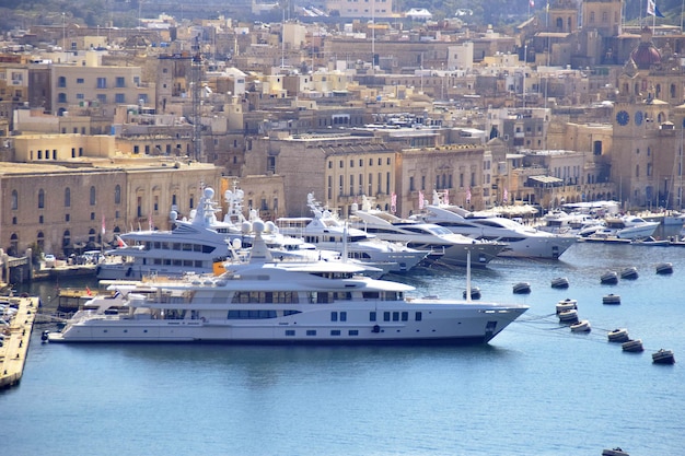 Un grande yacht bianco è attraccato in un porto con molte altre barche.