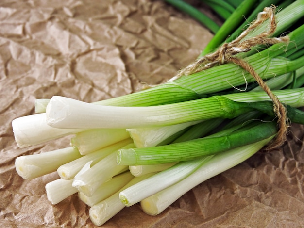 Un grappolo di cipolla verde su carta stropicciata.