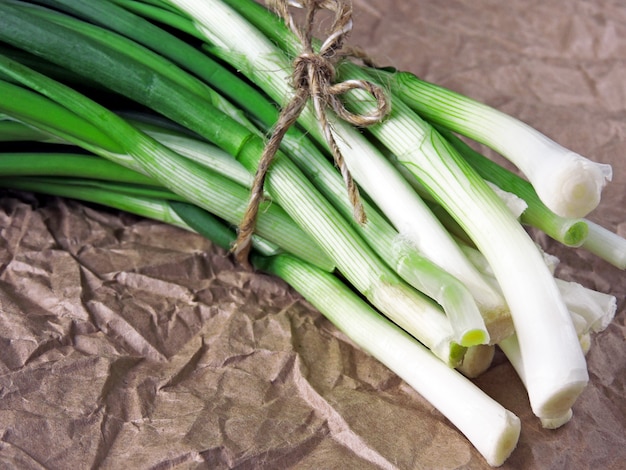 Un grappolo di cipolla verde su carta stropicciata.