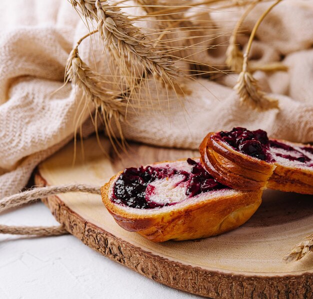 Un grosso panino con marmellata di ciliegie su una tavola di legno.