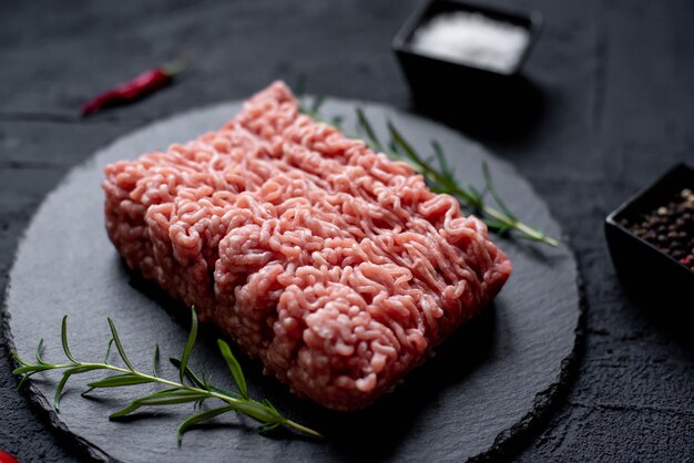 Un grosso pezzo di carne macinata è su un piatto di pietra nera.