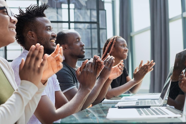 Un gruppo aziendale multietnico saluta qualcuno applaudendo e sorridendo