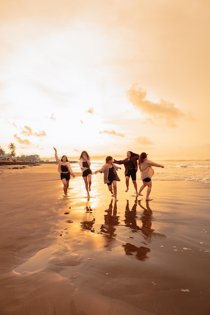 Un gruppo di adolescenti asiatici che corrono con espressioni felici in vacanza con i loro amici ubriachi sulla spiaggia