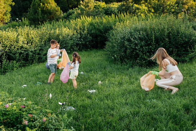 Un gruppo di adulti e bambini insieme al tramonto è impegnato nella raccolta dei rifiuti nel parco Riciclaggio dei rifiuti di tutela ambientale Smistamento dei rifiuti