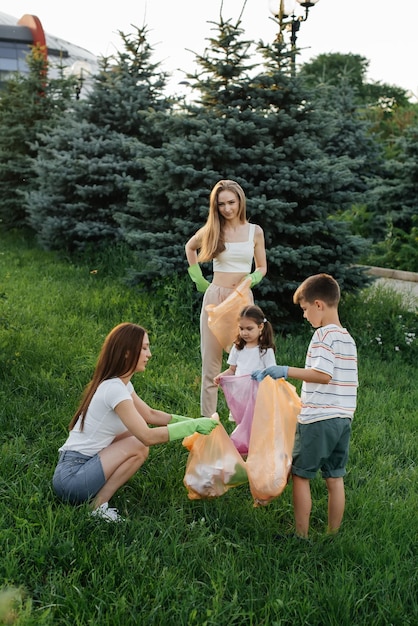 Un gruppo di adulti e bambini insieme al tramonto è impegnato nella raccolta dei rifiuti nel parco Riciclaggio dei rifiuti di tutela ambientale Smistamento dei rifiuti