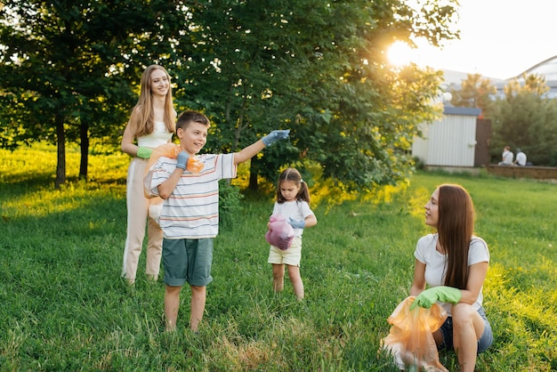 Un gruppo di adulti e bambini insieme al tramonto è impegnato nella raccolta dei rifiuti nel parco Riciclaggio dei rifiuti di tutela ambientale Smistamento dei rifiuti