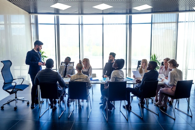 Un gruppo di afroamericani di successo europei arabi e uomini d'affari coreani e donne d'affari che lavorano in ufficio con grandi finestre di vetro