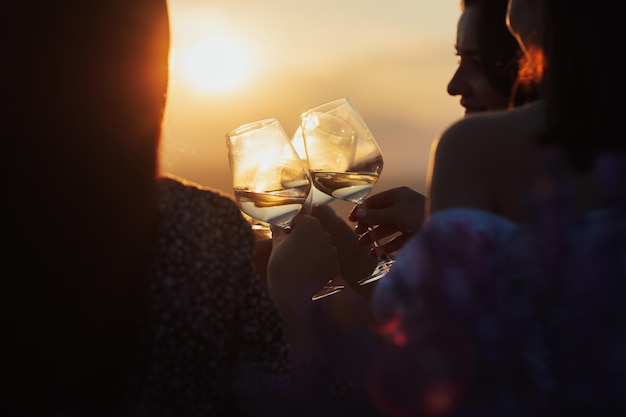 Un gruppo di amiche che tostano bicchieri di vino al tramonto