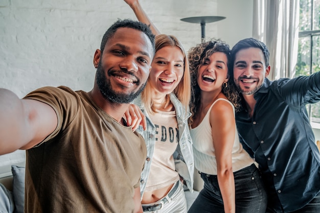 Un gruppo di amici diversi che si divertono mentre si scattano selfie insieme. Concetto di amici.