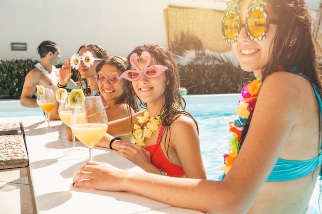 Un gruppo di amici in costume da bagno beve un cocktail in piscina