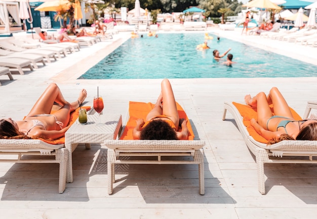 Un gruppo di amici in costume da bagno beve un cocktail in piscina