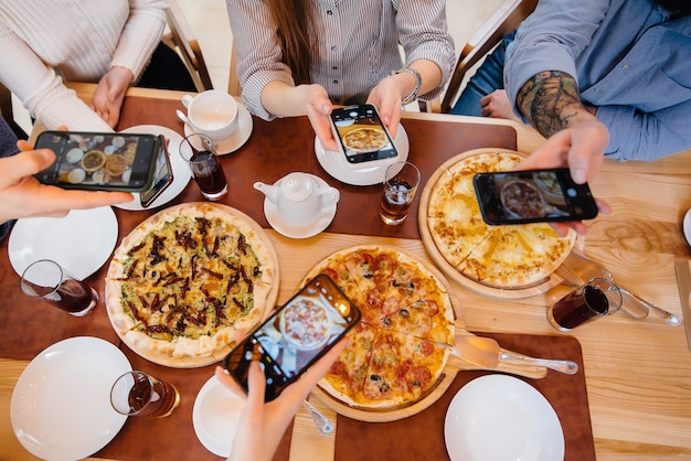 Un gruppo di amici scatta una foto ravvicinata di una deliziosa pizza per il blog, pizzeria.