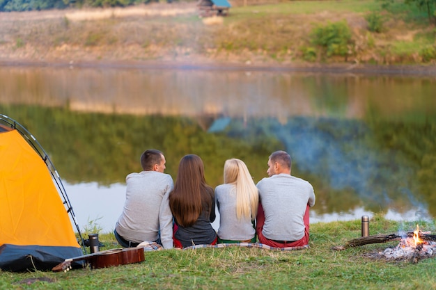 Un gruppo di amici si sta godendo la vista, accampandosi con il falò sulla riva del fiume