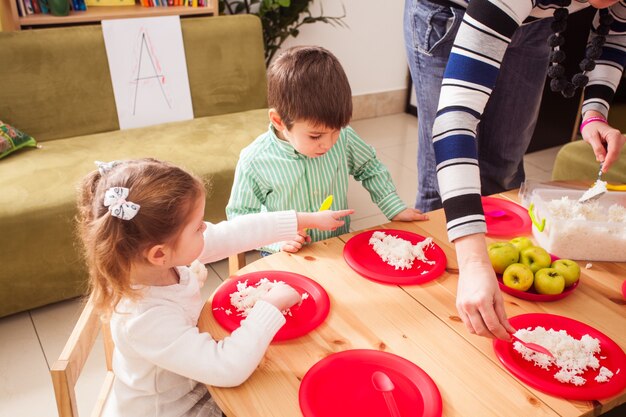 Un gruppo di bambini all'asilo seduti a un tavolo di legno e mangiando riso