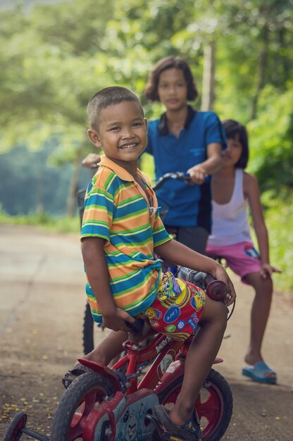 Un gruppo di bambini felici non definiti asiatici in sella alla loro bicicletta sulla strada