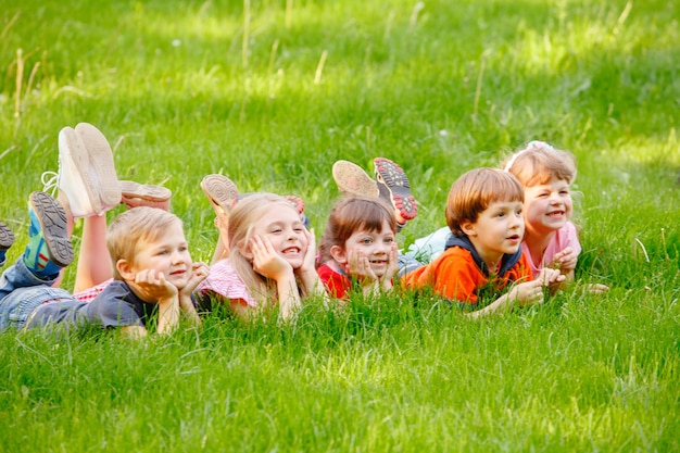 Un gruppo di bambini felici ragazzi e ragazze sdraiati nel parco sull'erba in una soleggiata giornata estiva.