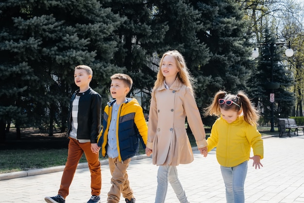 Un gruppo di bambini gioca insieme e cammina nel Parco tenendosi per mano. Amici, bambini