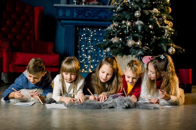 Un gruppo di bambini piccoli giace su una calda coperta di lana sullo sfondo di un albero di Natale