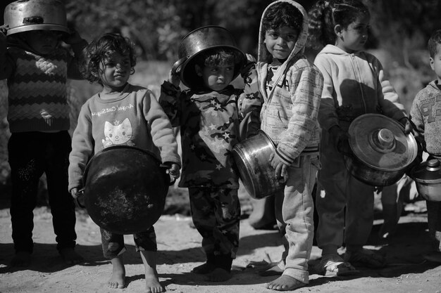 Un gruppo di bambini sta in fila con un gatto davanti a loro.