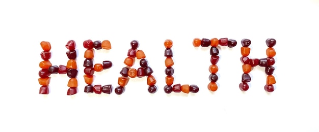 Un gruppo di caramelle gommose multivitaminiche rosse e viola disposte sotto forma di parola salute