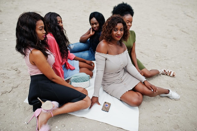 Un gruppo di cinque ragazze afroamericane che si rilassano sulla sabbia