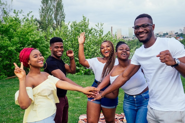 Un gruppo di cinque uomini e donne afroamericani sorridenti che camminano fuori dal tempo nuvoloso vicino al lago, scambiano studenti in Russia