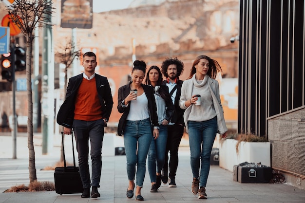 un gruppo di diversi giovani uomini d'affari in pausa dal lavoro girano per la città, usano smartphone, ascoltano musica e si divertono