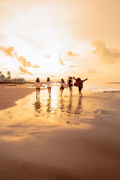 Un gruppo di donne asiatiche corre felicemente con i loro amici sulla spiaggia