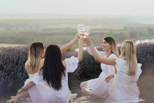 Un gruppo di donne vestite di bianco è seduto su un prato e sta brindando