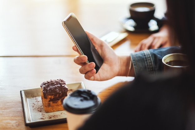 Un gruppo di giovani asiatici che usano e guardano lo stesso telefono cellulare insieme al bar