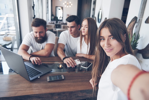 Un gruppo di giovani con gadget e un laptop organizza un brainstorming e comunica tra loro. Il concetto di sviluppo di una giovane impresa