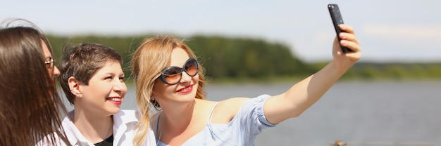 Un gruppo di giovani donne su una barca che si gode una giornata di sole e si fa un selfie al telefono